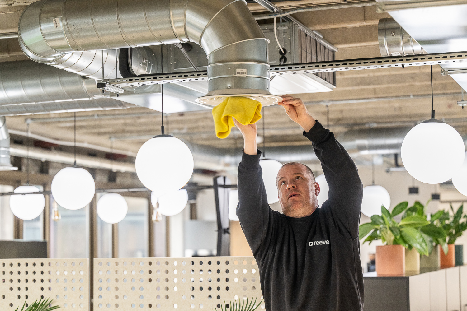A Reeve operative cleaning an office air-handling vent